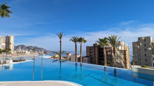 una grande piscina con palme e edifici di SUNSET CLIFFS sea view apartments a Benidorm
