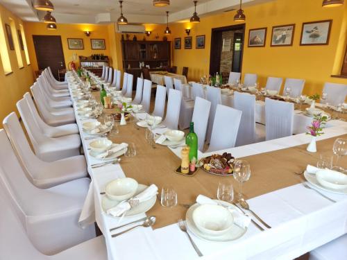 a long dining room with white tables and white chairs at Pri štorklji in Moravske-Toplice