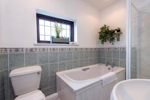 a bathroom with a tub and a toilet and a sink at Linden Cottage in Coxhoe