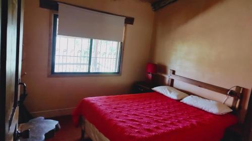 a bedroom with a red bed with a window at El Gran Chaparral in Siguatepeque