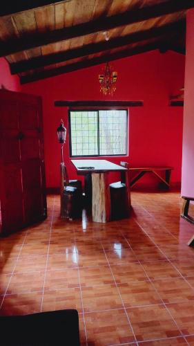 Habitación con mesa y pared roja. en El Gran Chaparral en Siguatepeque