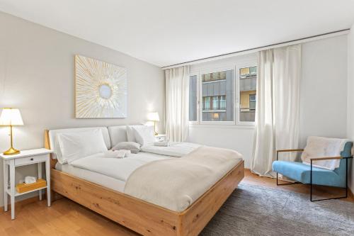 ein Schlafzimmer mit einem großen Bett und einem blauen Stuhl in der Unterkunft Bright, Central & Modern apartment in Luzern