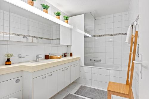 a white bathroom with a sink and a tub at Bright, Central & Modern apartment in Lucerne