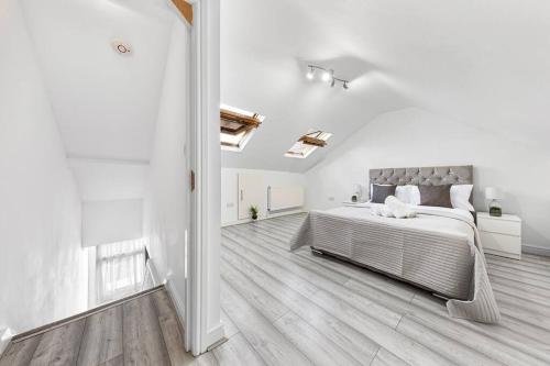 ein weißes Schlafzimmer mit einem großen Bett und Holzböden in der Unterkunft Ultra Elegant 2BDR - 10 mins to stadium - Sleeps 5 in London