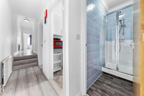 baño con ducha a ras de suelo y azulejos azules en Ultra Elegant 2BDR - 10 mins to stadium - Sleeps 5, en Londres