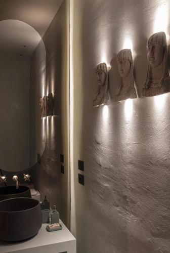 a bathroom with a sink and some masks on the wall at ELLE dimora di Sicilia in Catania