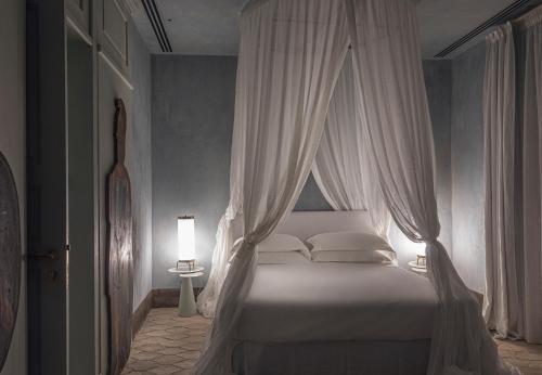 a bedroom with a white canopy bed with white pillows at ELLE dimora di Sicilia in Catania