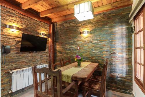 a dining room with a table and a tv on a brick wall at Cabañas Tierra Mistica in Ushuaia