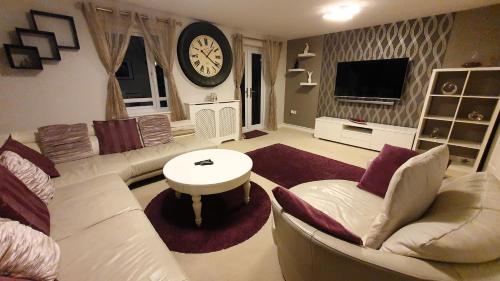 a living room with a couch and a clock on the wall at Entire home in Cheswick Village in Bristol