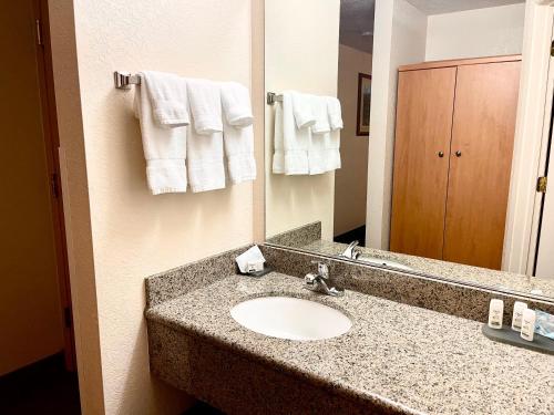 een badkamer met een wastafel, een spiegel en handdoeken bij Wenatchee Inn in Wenatchee