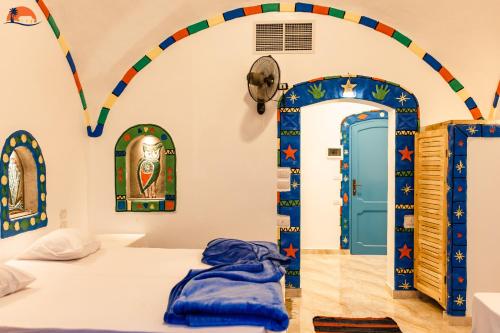 a room with a bed with an arch and a door at Nuba Narty in Aswan