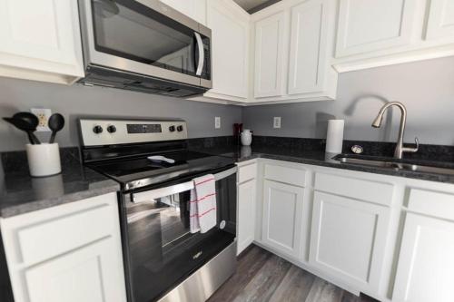 a kitchen with white cabinets and a stove and a microwave at Lady Hoosier Retreat in Bloomington