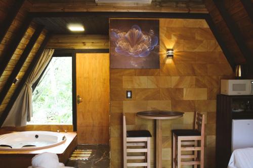 baño con bañera, mesa y ventana en Chalé Suiço com Hidromassagem e café da Manhã, en Praia Grande