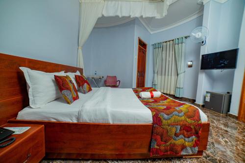 ein Schlafzimmer mit einem großen Bett und einem Schreibtisch mit einem Laptop in der Unterkunft Entuiga cottages in Hoima