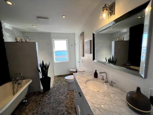 a bathroom with a sink and a tub and a toilet at Private Kingston Waterfront Home in Kingston