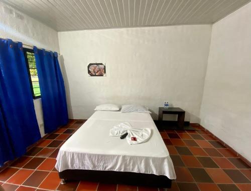 a bed in a room with blue curtains at El Palmar in Guaduas