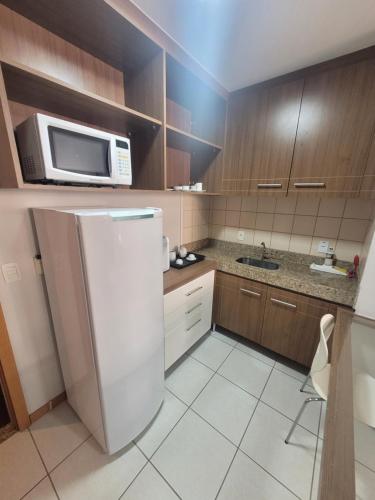 a kitchen with a white refrigerator and a microwave at Flat Nobile Suítes Monumental By Rei dos Flats, in Brasilia