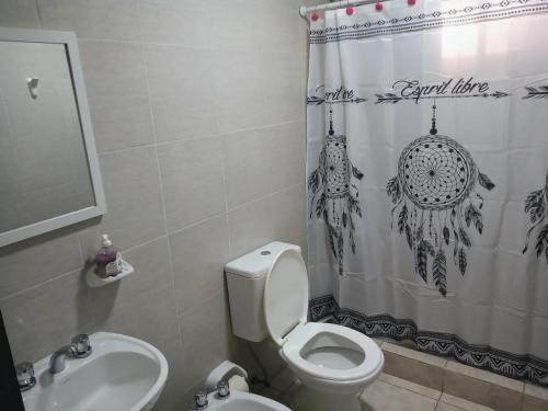 y baño con aseo, lavamanos y cortina de ducha. en Monoambientes Arandu en Federación