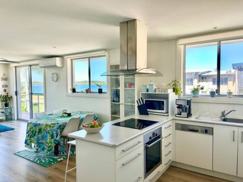 a kitchen with white cabinets and a table with a counter at Cosy unit with park & water view in Ballina