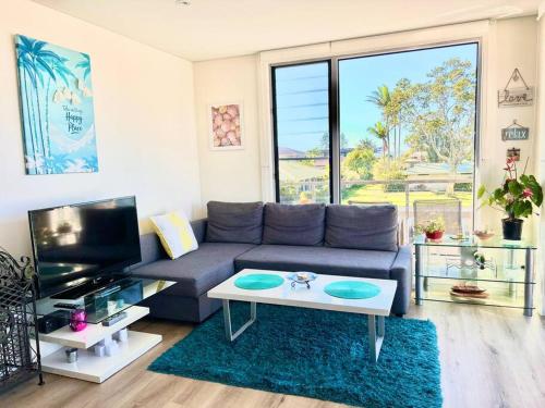 a living room with a couch and a tv at Cosy unit with park & water view in Ballina