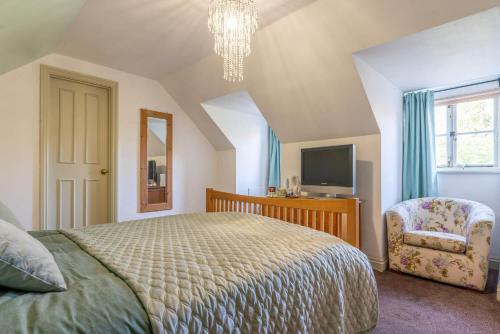 - une chambre avec un lit, une chaise et une télévision dans l'établissement The Crown Inn, à Sarre