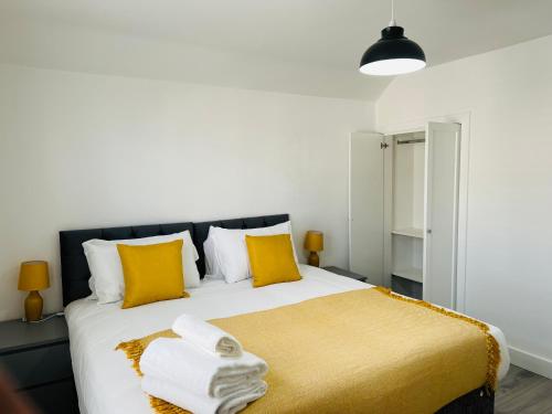 ein Schlafzimmer mit einem großen Bett mit gelben Kissen in der Unterkunft Beautiful, Luxurious 3 Bed house, Perfect for Contractors , Family & Friends in Dartford