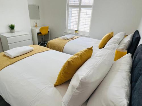 two beds in a bedroom with white and yellow pillows at Beautiful, Luxurious 3 Bed house, Perfect for Contractors , Family & Friends in Dartford