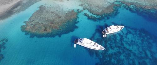 dois barcos na água ao lado de uma pequena ilha em New Sambo Liveaboard em Marsa Alam