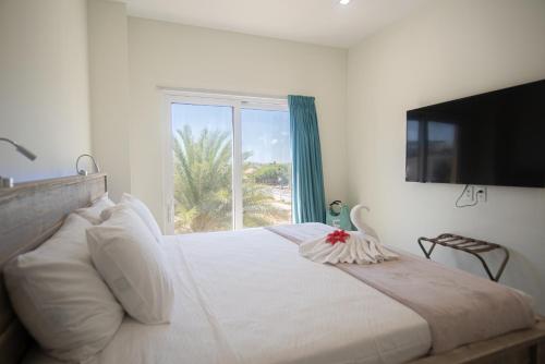 um quarto com uma grande cama branca e uma janela em The Cove - Condo Hotel - Palm Beach Strip em Palm Beach