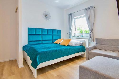 a bedroom with a blue bed and a couch at Apartament "Szczęśliwa 13" in Dziwnówek
