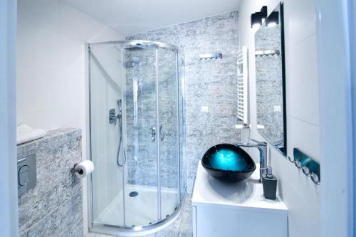 a bathroom with a shower and a black bowl on a sink at Apartament "Szczęśliwa 13" in Dziwnówek