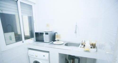 a white kitchen with a sink and a microwave at Appartement entier F3 climatisé agréable, spacieux et confortable à Gadaye in Dakar