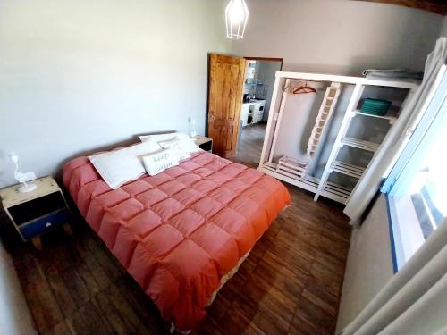 a bedroom with a bed with an orange blanket at Cabaña Gota de Rocio en finca Margarita in San Rafael