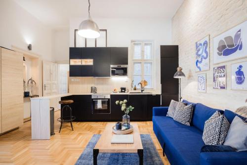 sala de estar con sofá azul y cocina en Historic Penthouse with Sauna & Jacuzzi @Downtown, en Budapest