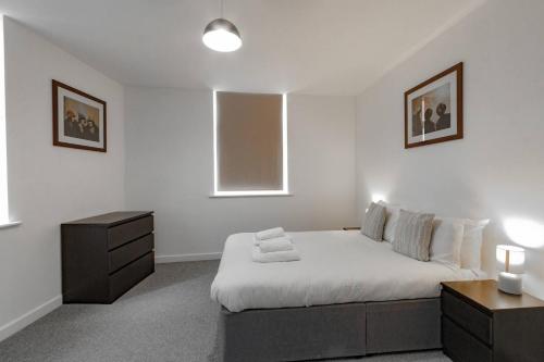 Heywood的住宿－Comfy 1BR Apartment with Great Amenities，一间白色卧室,配有床和床头柜