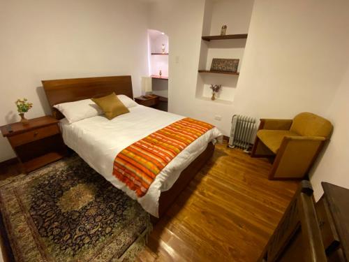 a bedroom with a large bed and a chair at Hotel Colonial - Casa Francisco in Quito