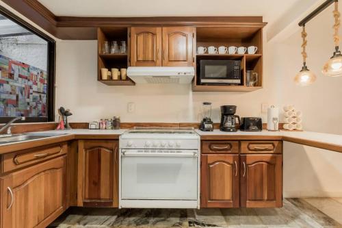 a kitchen with wooden cabinets and a white stove top oven at *Villa Sicilia Lagoon front by Casa Paraiso* in Cancún
