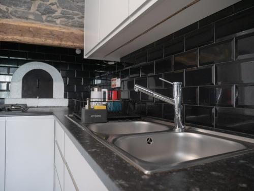 a kitchen with a sink and a black tile wall at Isabela House in Ponta do Sol