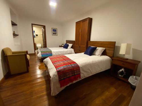 a hotel room with two beds and a chair at Hotel Colonial - Casa Francisco in Quito