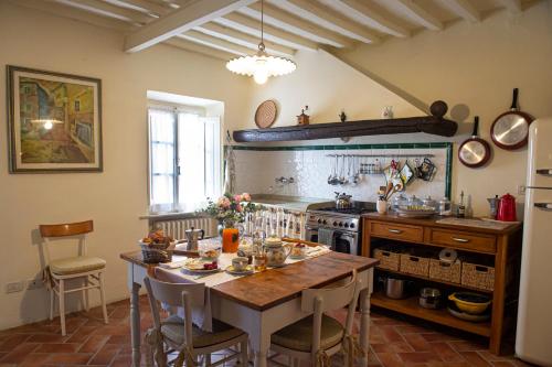 una cucina con tavolo in legno e una cucina con piano cottura di La Casetta Di Borgo a Laiatico