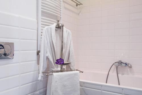 a white bathroom with a towel and a bath tub at Royal Apartament in Krakow