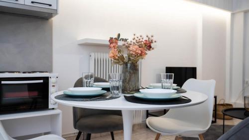 a white dining room table with plates and flowers on it at La casa Nikol Meteora in Kalabaka