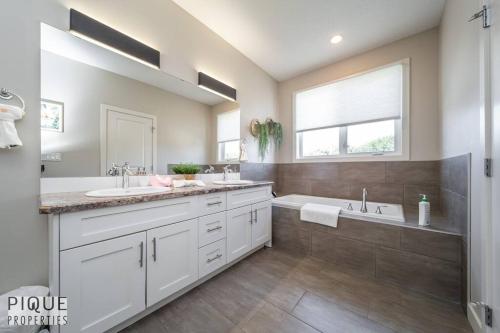a white bathroom with two sinks and a tub at BoHo Vibes - Patio & BBQ - King Bed - Garage Parking in Edmonton