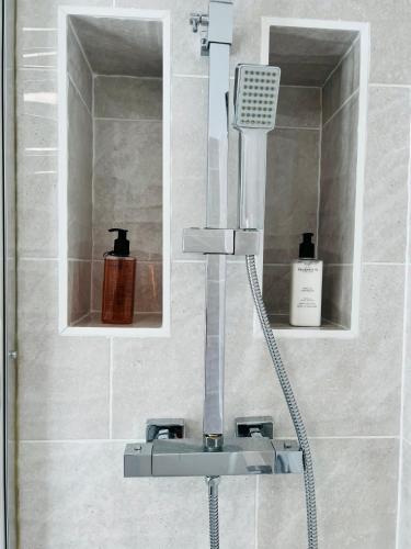 a shower head in a bathroom with two mirrors at Beautiful, Luxurious 3 Bed house, Perfect for Contractors , Family & Friends in Dartford