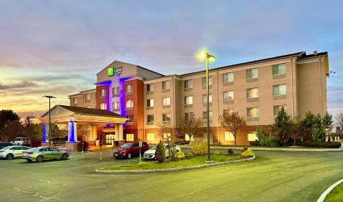 a hotel with cars parked in a parking lot at Holiday Inn Express & Suites Dewitt - Syracuse by IHG in East Syracuse