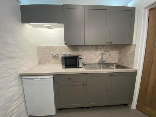 a kitchen with a sink and a microwave at Victorian Police Station Apartment in Launceston