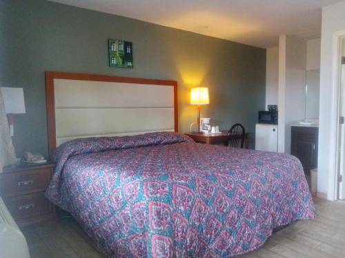 een slaapkamer met een groot bed met een kleurrijke sprei bij Maple leaf motel in New Milford