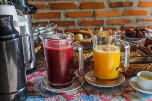 twee glazen sap zittend op een tafel bij Chalé Suiço com Hidromassagem e café da Manhã in Praia Grande