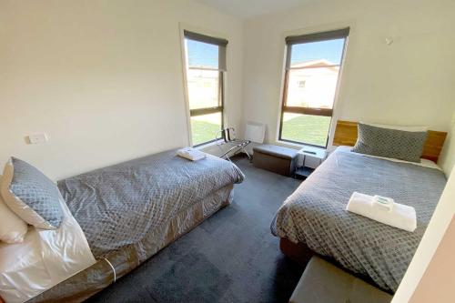 1 dormitorio con 2 camas y 2 ventanas en Wild Rivers Escape en Strahan