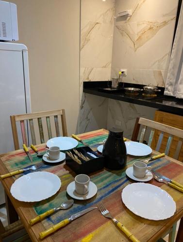 a wooden table with plates and utensils on it at Villa Licuri Boiçucanga in Boicucanga
